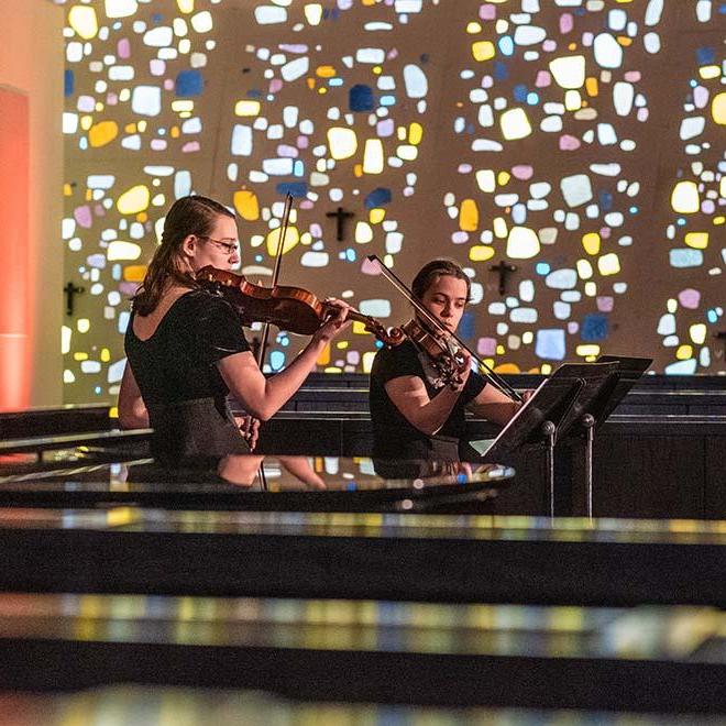 Two string musicians playing in the Our Lady of the Annunciation Chapel