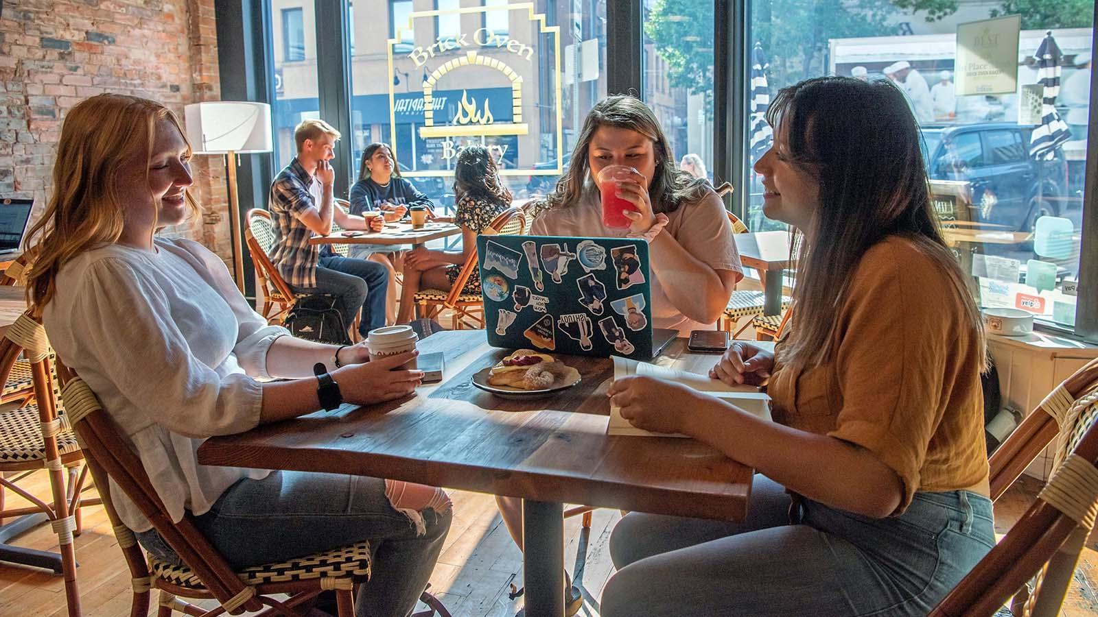 Three female students enjoying coffee and pastries at Brick Oven Bakery in downtown Bismarck